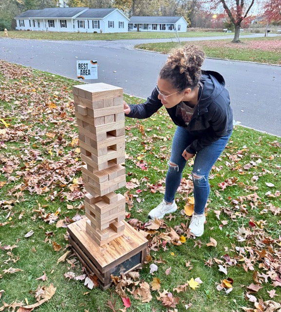 adult playing giant jenga outside