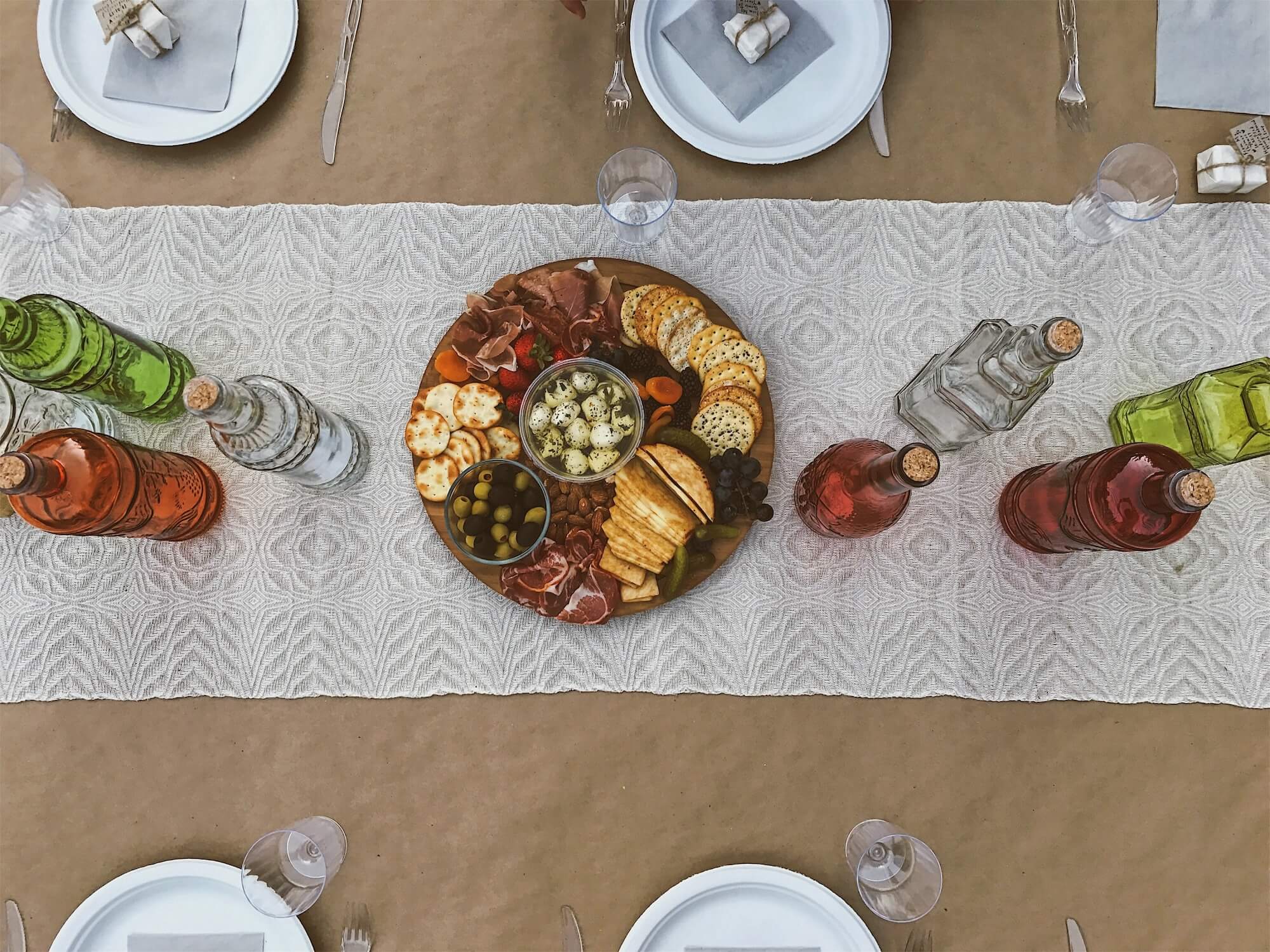 charcuterie board with place settings and bottles on table at event