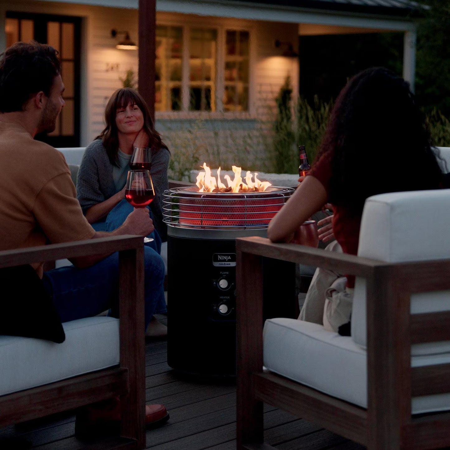 People sitting around a fire pit on a patio at night