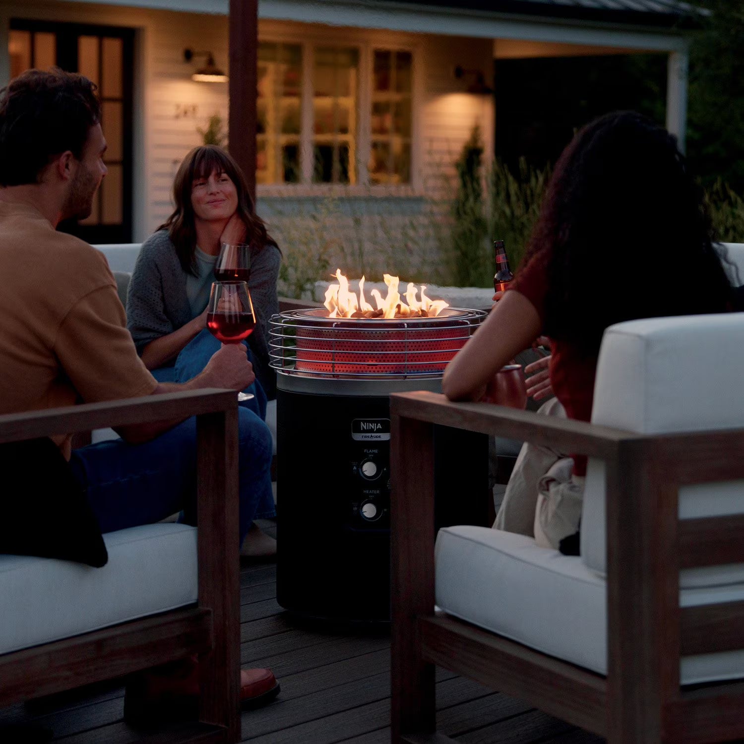 People sitting around a fire pit on a patio at night